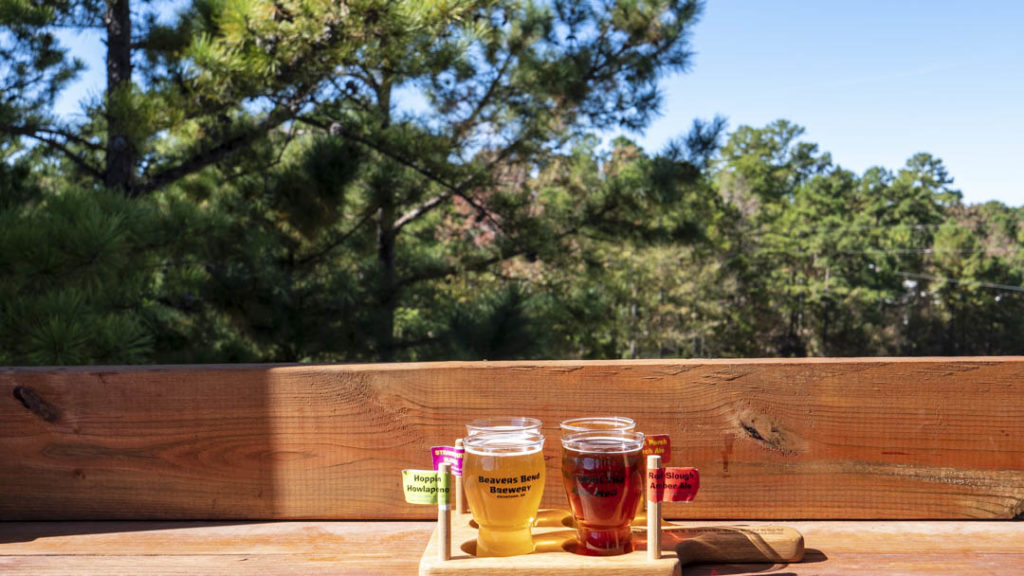 A photograph of the view from Beavers Bend Brewery during the day while a flight of beers on a table.