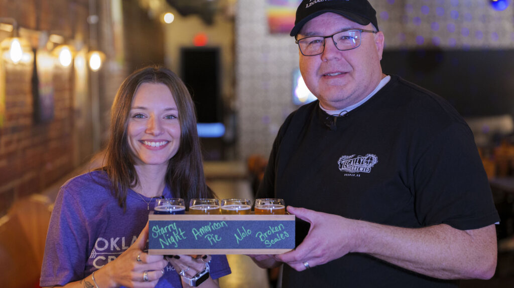 Photo of Bri helping hold of a flight of beers with Tracy Mowdy from Legally Brewed.