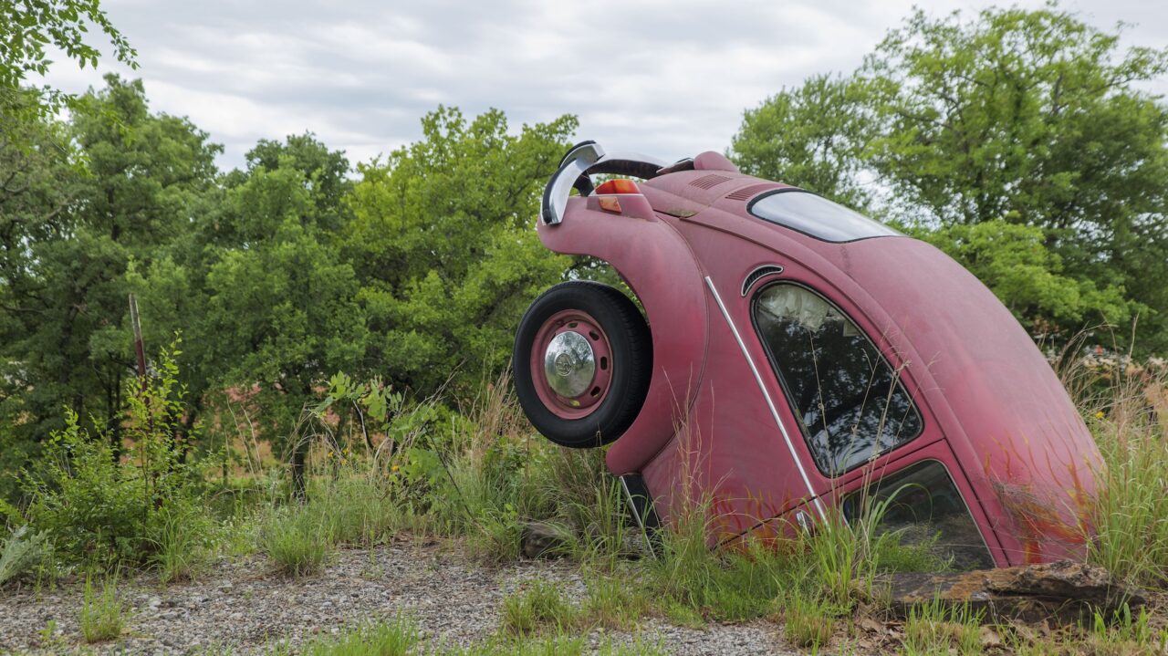 Photo of a red car sticking up from the ground.