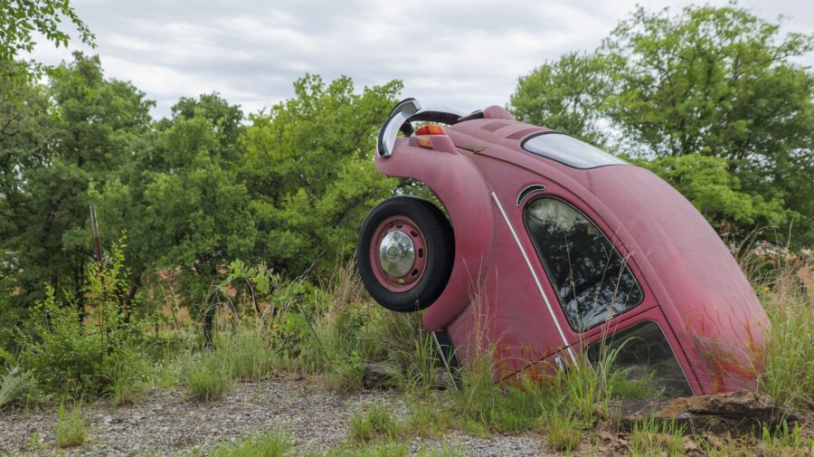 Photo of a red car sticking up from the ground.